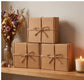 Eco-friendly skincare gift boxes with twine bows, dried flowers, and a candle on wooden shelf